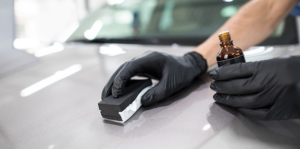 Wearing protective gloves, the technician is applying ceramic coating to the surface of Toyota Corolla.