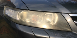 Foggy headlights of a black Saab sedan vehicle.