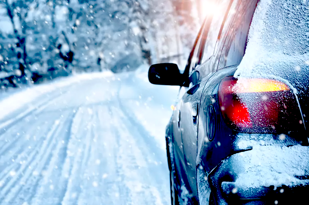 Family vehicle a hatchback Subaru driving on a snowy road.